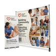 A Toronto Heart Foundation promotional banner display setup on a white background, showing a large printed backdrop and a matching roll-up sign. The printed design includes a red heart logo, the text 'Building Community Care' and 'Supporting Your Health, Together,' plus multiple care worker and community photos.